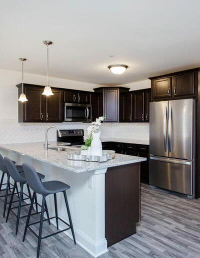 modern condo kitchen with stainless appliances, stone countertops, and bar-style seating