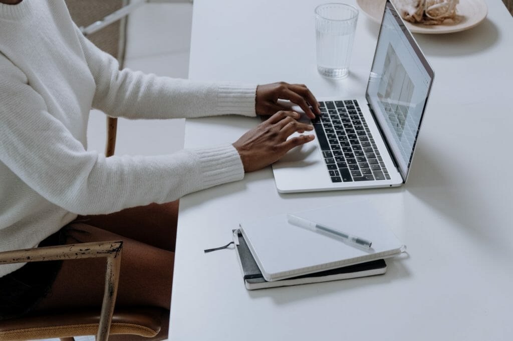 A person in a white sweater using a laptop