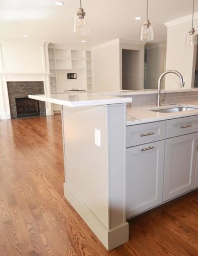 modern kitchen with stone countertops that opens into a living room with a stone fireplace