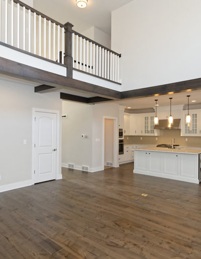 great room looking into kitchen and walkway upstairs