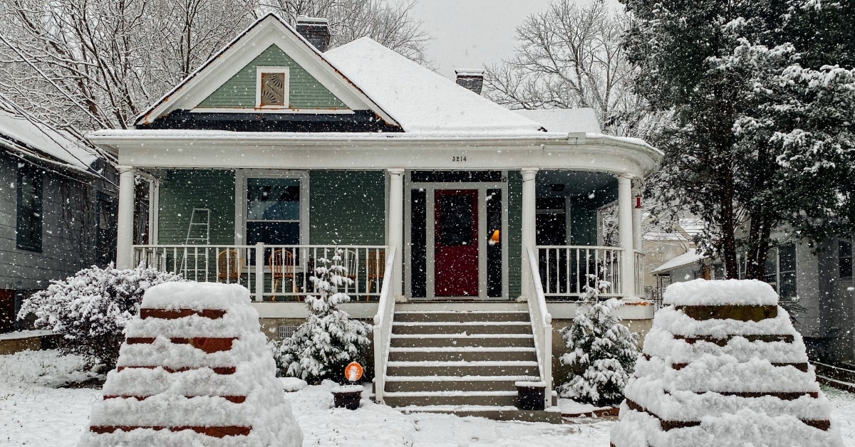 small house with wraparound porch in the winter