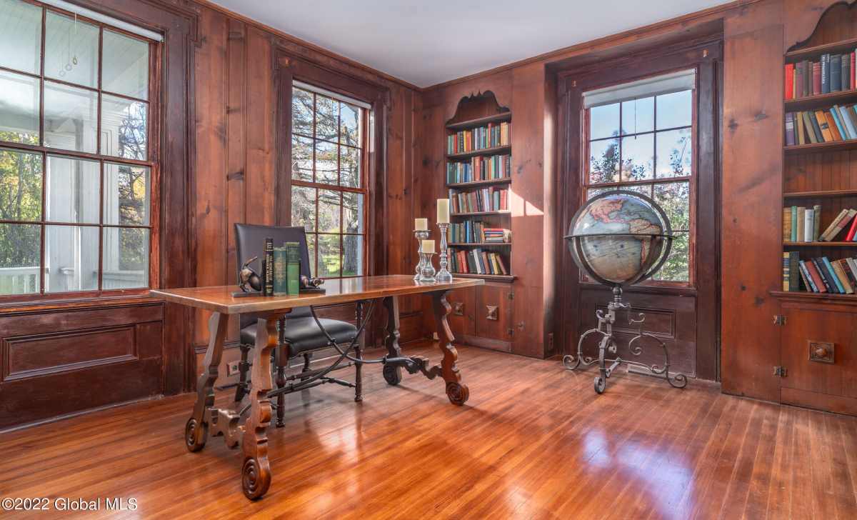 an office space with bookshelves, a large globe, and a desk