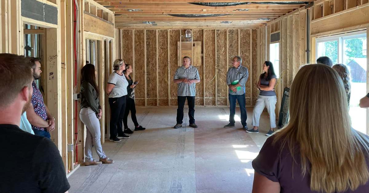 group of people stand in a house partially under construction