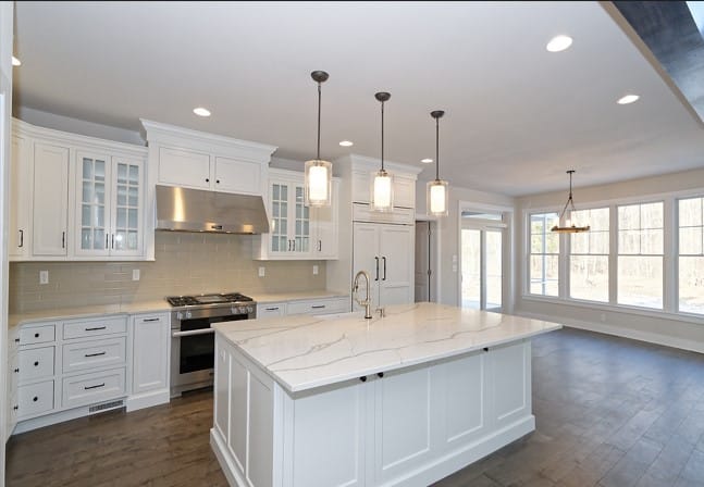 kitchen with white quartz countertops and white cabinets and 3 pendant lights