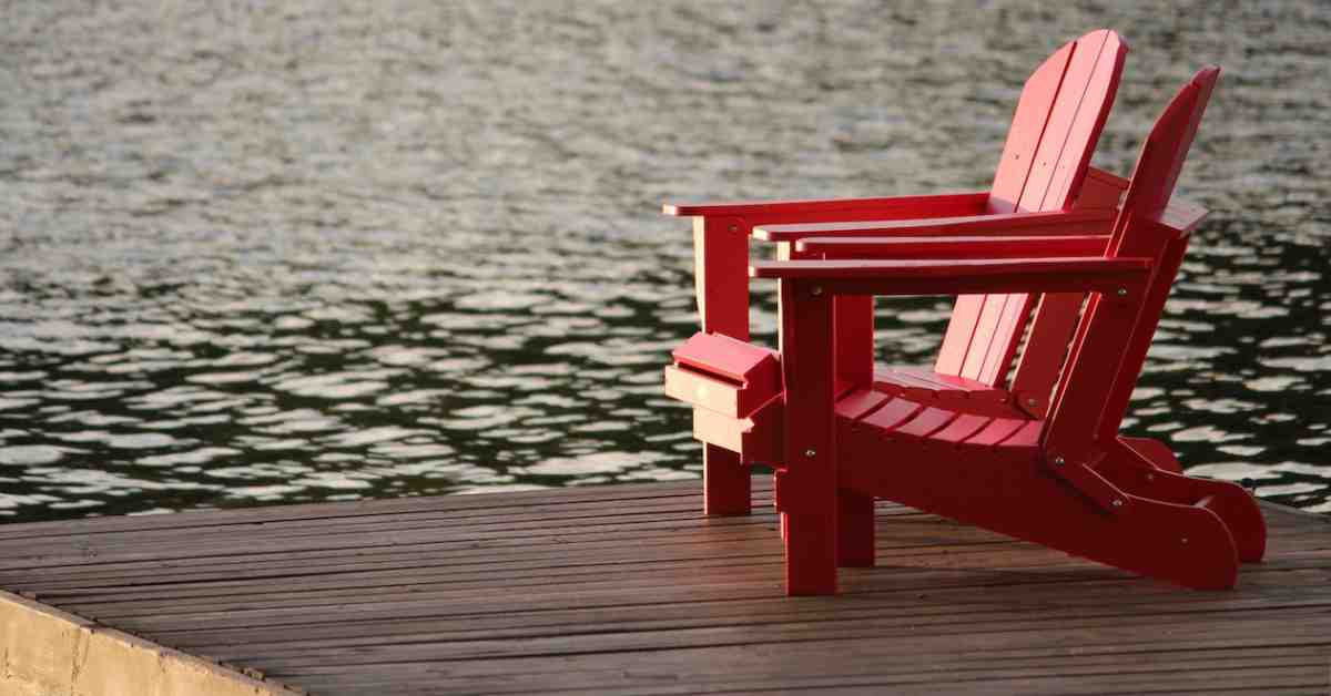 two red adirondack chairs on lake dock