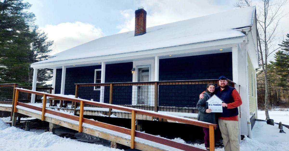 man and woman standing in front of a home during a snowy day