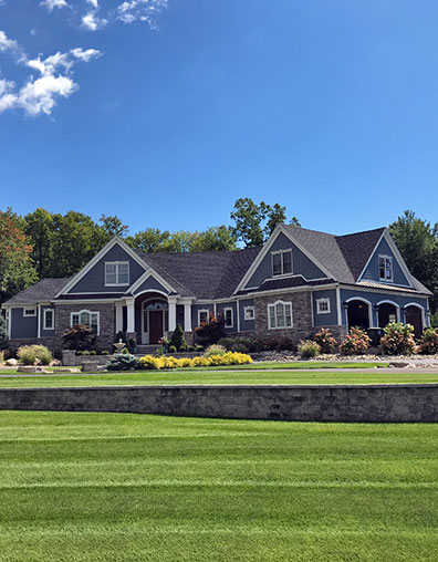 large estate home with blue siding and rock facade